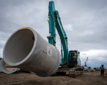 Excavator moving pipe with pipe lifter